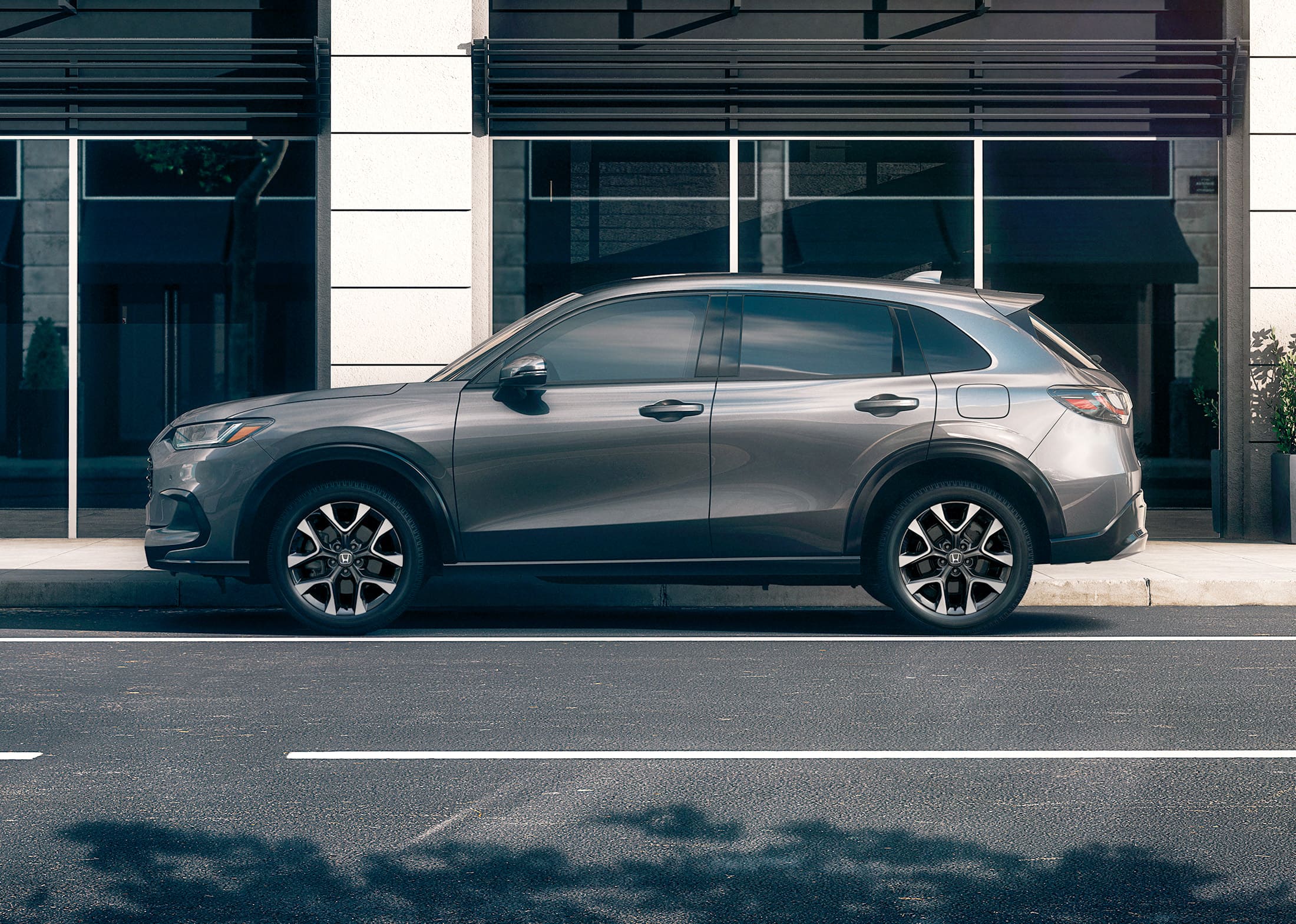 Driver-side profile shot of the 2026 Honda HR-V EX-L in Modern Steel Metallic, shown parked on an urban street.